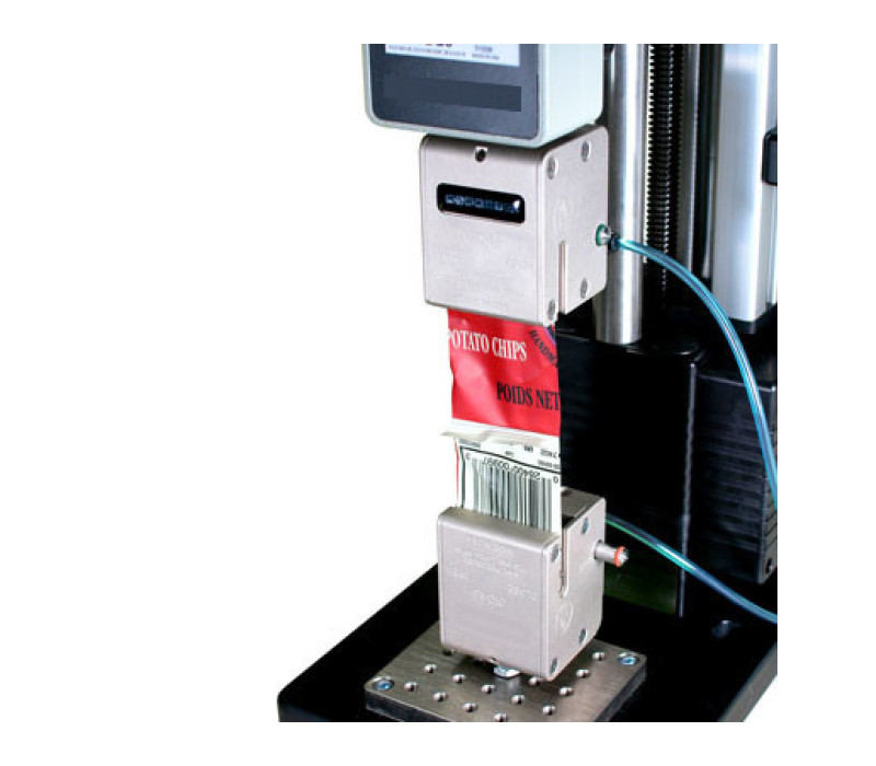 Pair of G1046 grips shown in a typical 180° peel test of a sealed package strip, used in conjunction with a digital force gauge and test stand.