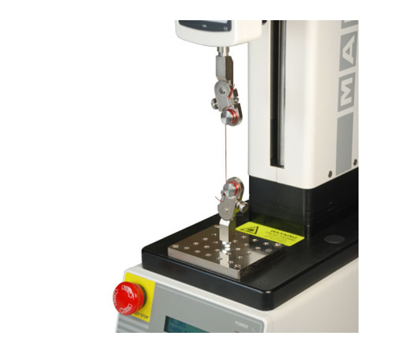 Pair of G1078 grips shown in a typical pull testing application, shown mounted to a motorized test stand with digital force gauge.